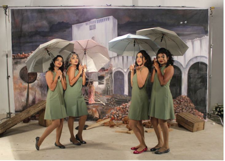 4 girls of different ethnicities standing in sage green dresses with umbrellas