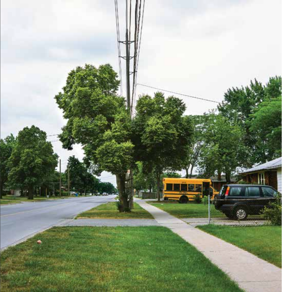 a suburban street with a small yellow bus in a driveway