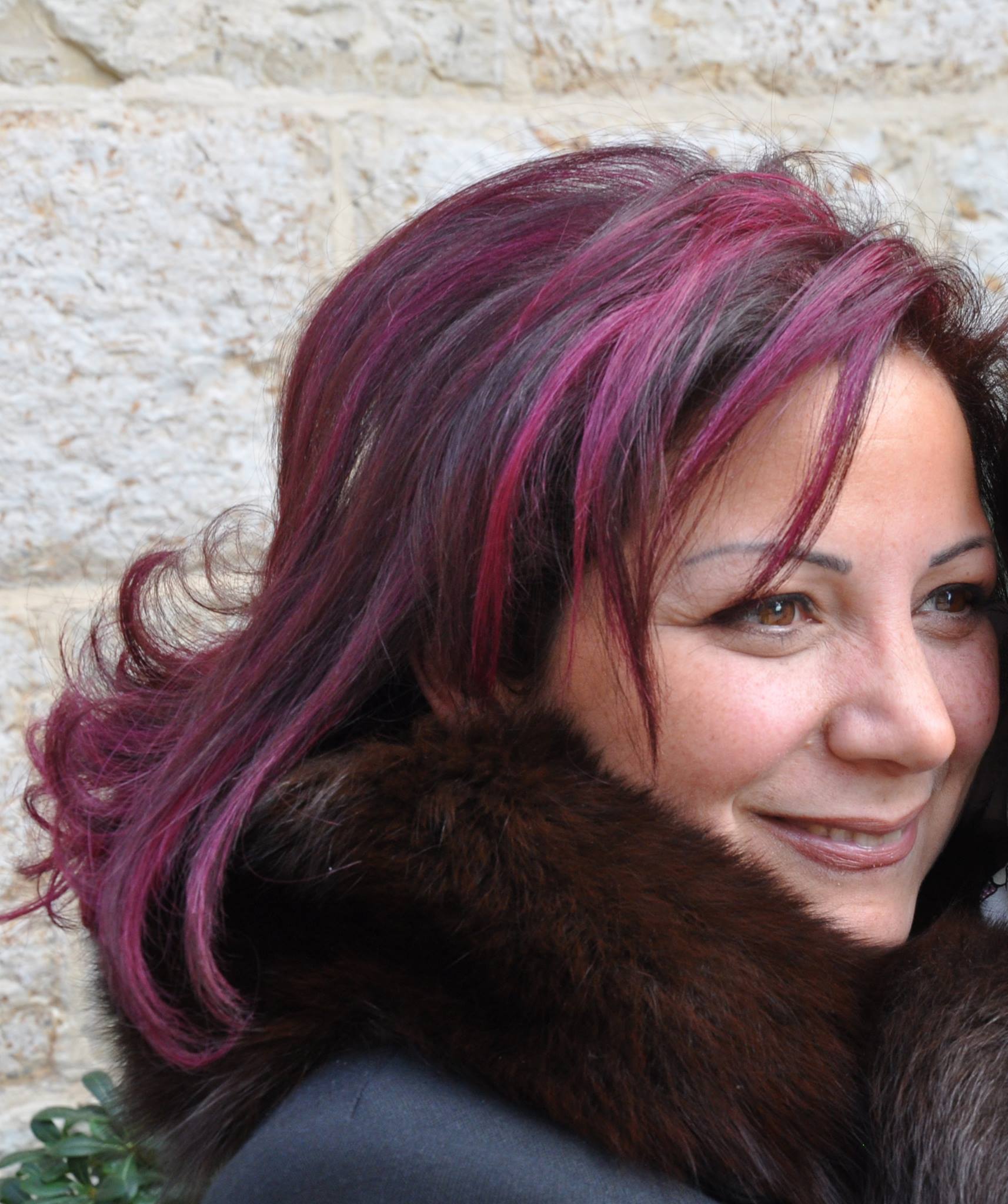 : a woman with pink highlighted hair wearing a black fur jacket. 