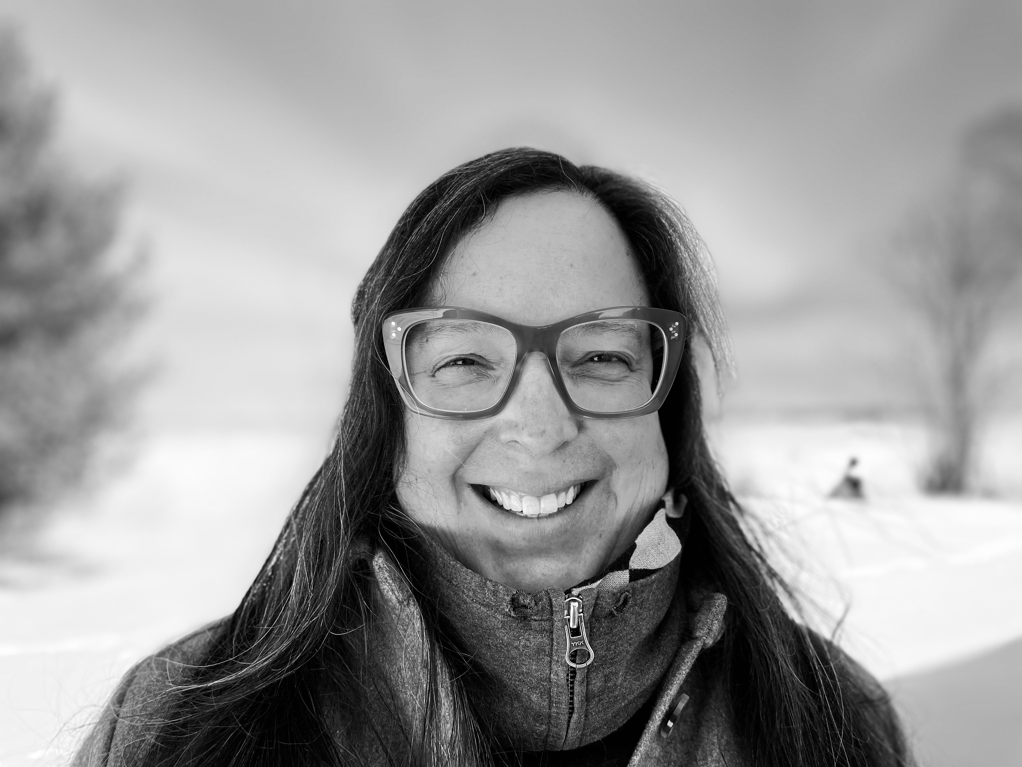 A woman smiling wearing eyeglasses with shoulder length black hair