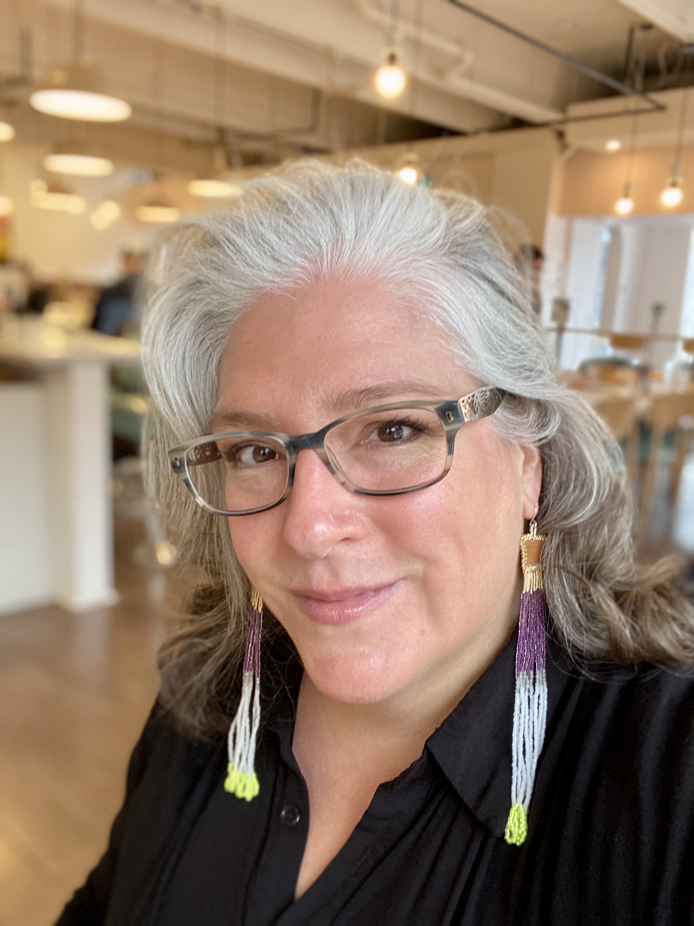 A woman smiling wearing eyeglasses with shoulder length gray hair