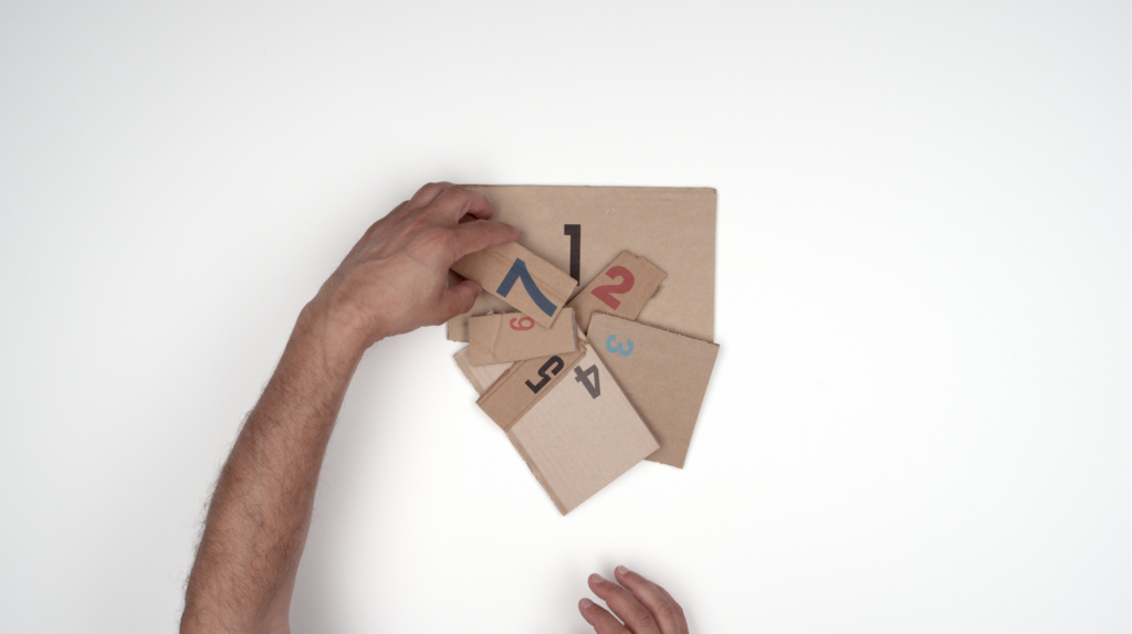 A film still of a hand holding a piece of cardboard with numbers.