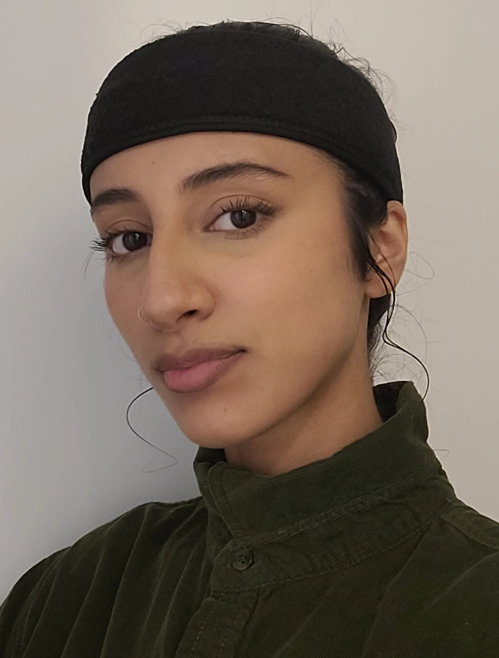 a woman wearing black hair covering with black turtle neck shirt. 