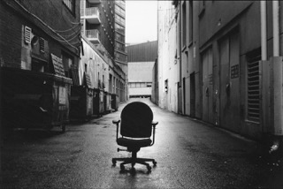black and white photo of an office chair in an alley