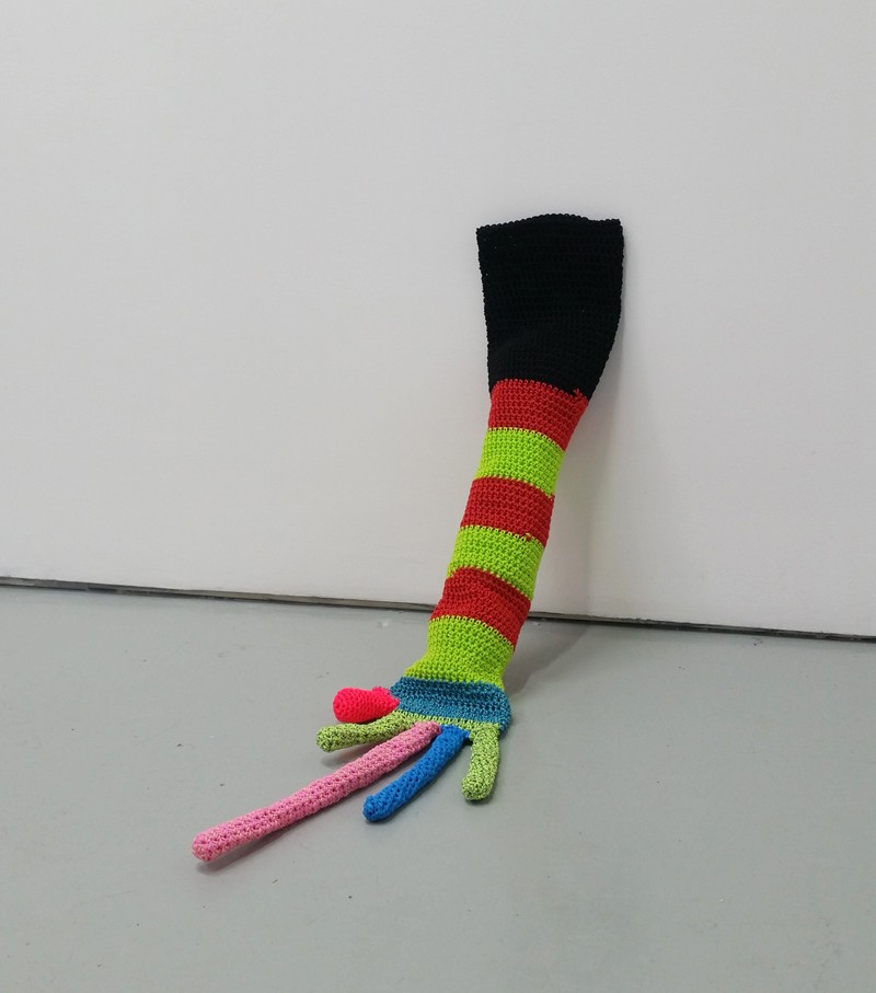 Photo of a multi-coloured knit glove leaning on a wall