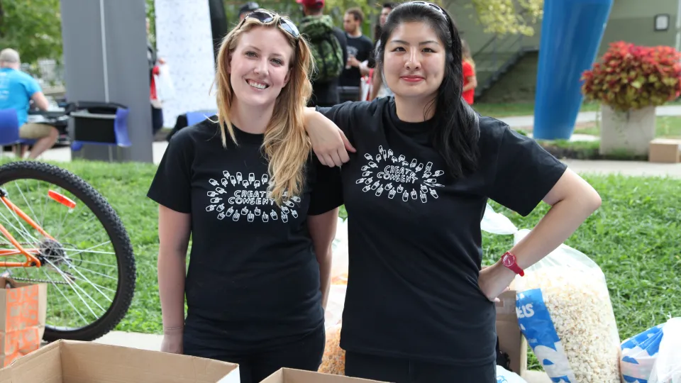 Two people smiling in black t-shirts.