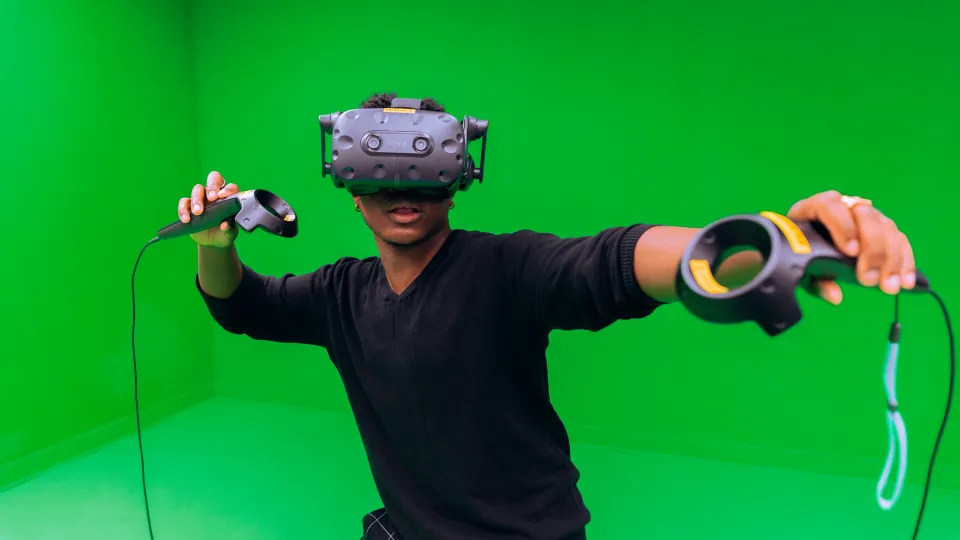 A young person wearing a VR headset on a green background.