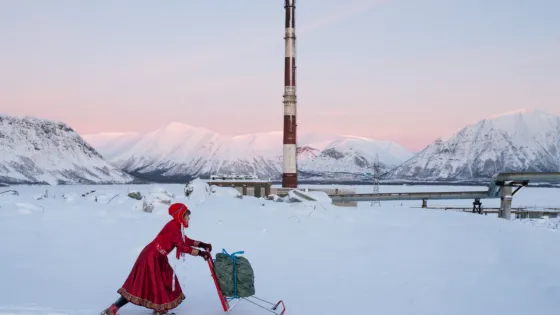 A woman pushing a shopping cart in the snow.