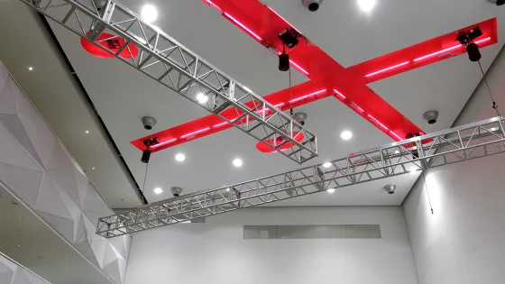 Ceiling of the Great Hall with lighting rigs and a bold red X architectural detail