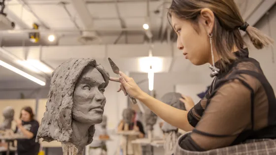 Person working on a clay sculpture.