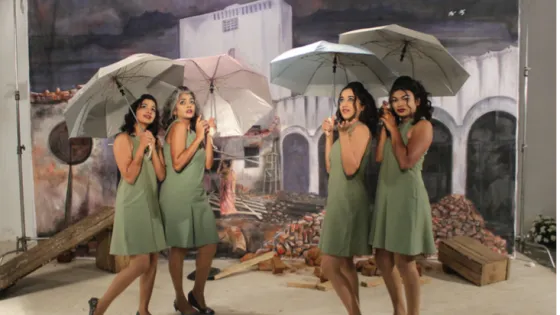 4 girls of different ethnicities standing in sage green dresses with umbrellas