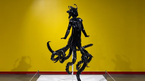 Installation view, Ekow Nimako, Maame Wata, 2023, 64 x 40 x 45 in, LEGO®, metal armature. Photo by Em Moor. Black sculpture in front of yellow wall. 