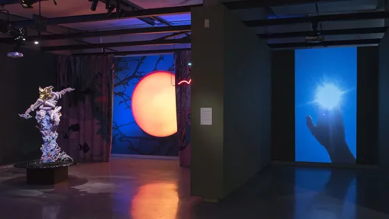 A dark room with blue light, orange light and a sculpture