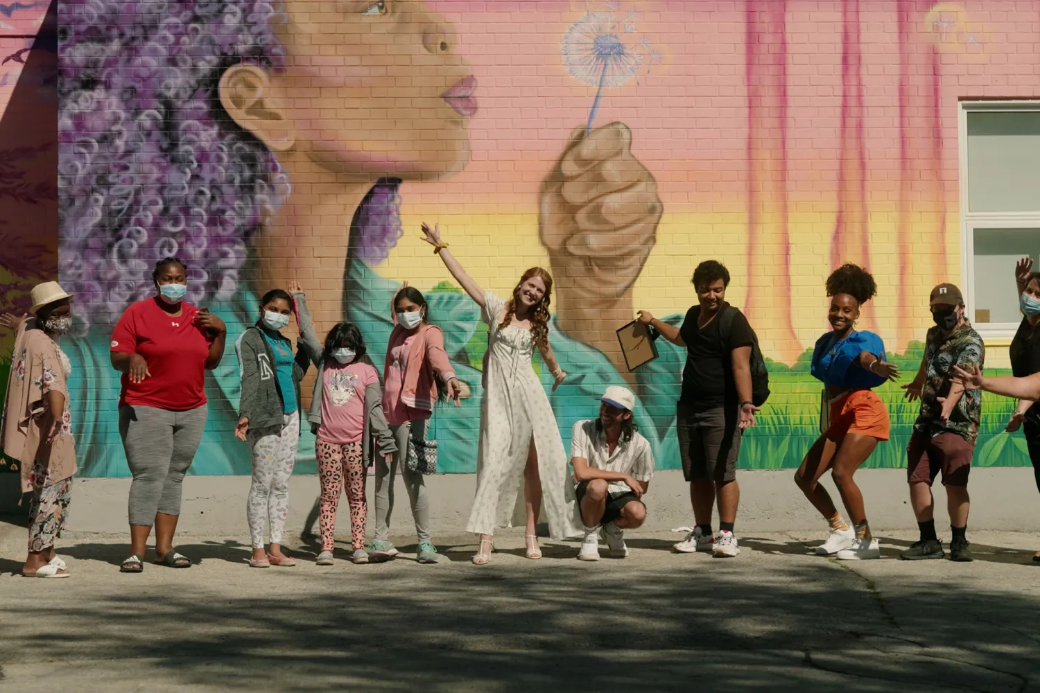 Group of people posing in front of a mural.