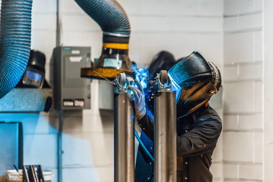A student welding wheels to a post.