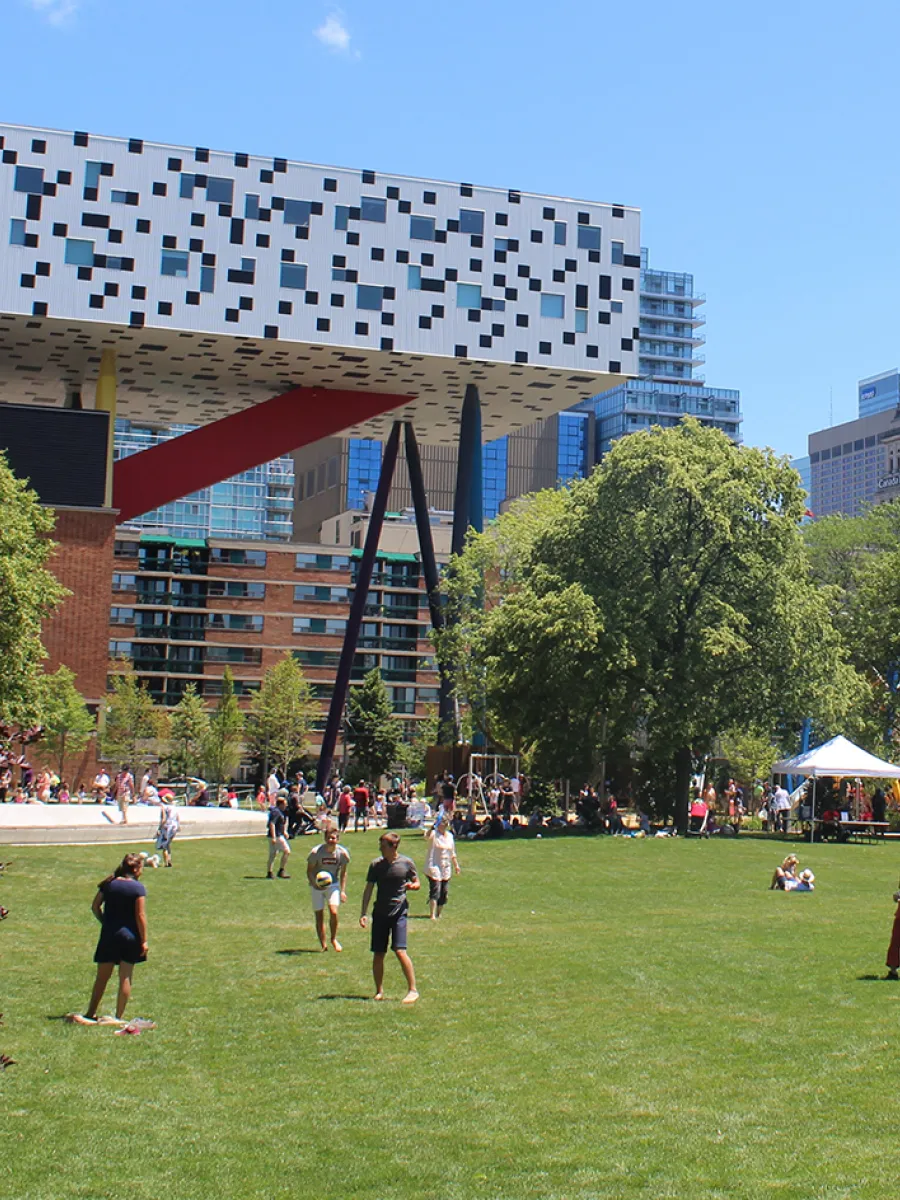 People playing ball on a field with a black and white checkered building on stilts.