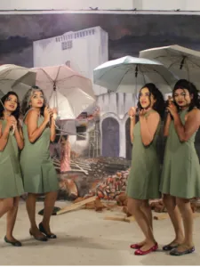 4 girls of different ethnicities standing in sage green dresses with umbrellas