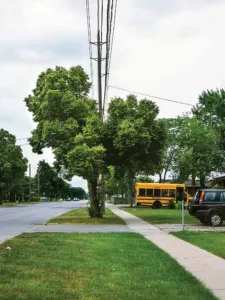 a suburban street with a small yellow bus in a driveway