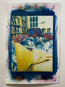 this is a colour print with a portrait orientation \ a black &amp; white dog \ S \ a whippet is centred \ laying on a couch snuggled in blankets &amp; pillows \ in the background there is a bookcase \ a light \ and a cup of tea to the right of the print is a handwritten poem \ which could be understood as the beginnings of an escape into drawing