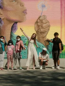 Group of people posing in front of a mural.