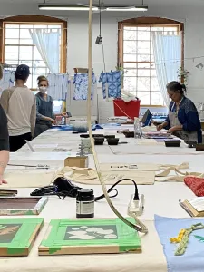 A group of people working around a table in the Contemporary Textile Studio.