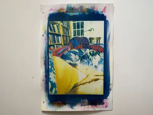 this is a colour print with a portrait orientation \ a black &amp; white dog \ S \ a whippet is centred \ laying on a couch snuggled in blankets &amp; pillows \ in the background there is a bookcase \ a light \ and a cup of tea to the right of the print is a handwritten poem \ which could be understood as the beginnings of an escape into drawing