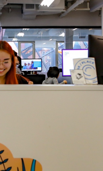 People smiling behind a sign that reads "hello".