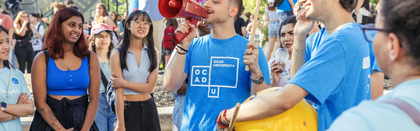 People outside, smiling at a person with a bullhorn.