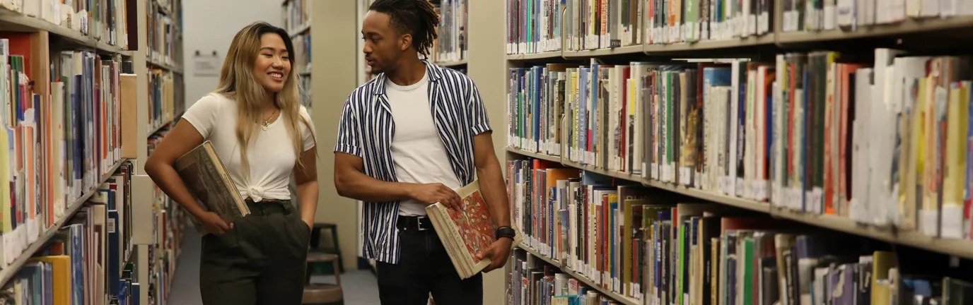 Two people walking through library stacks