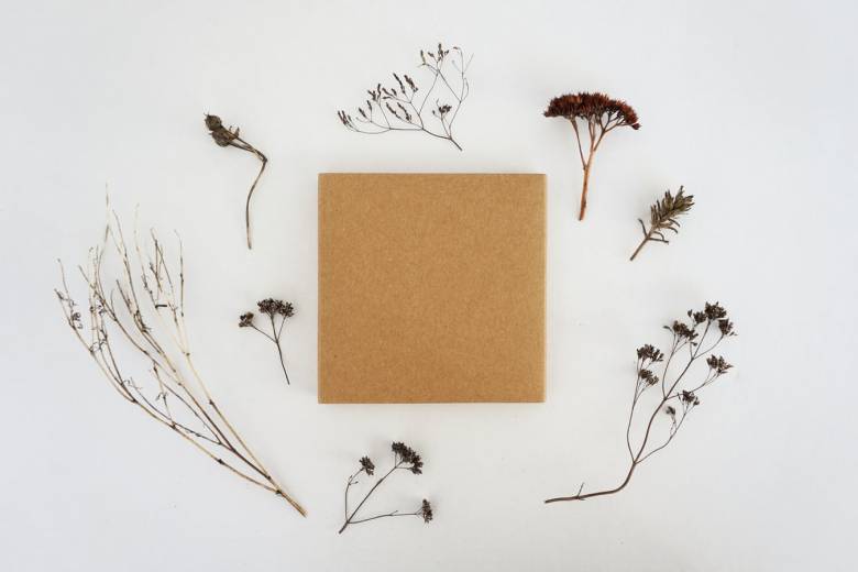 A photograph of a brown box in the centre, encircled by dried flowers, on a white background.