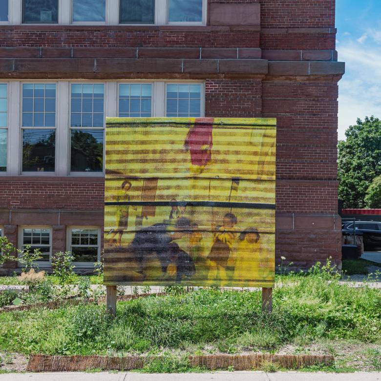 Photograph by Aman Deshmukh of Ernesto Cabral de Luna's work displayed on the public billboard on 180 Shaw St. Brick building in the background.