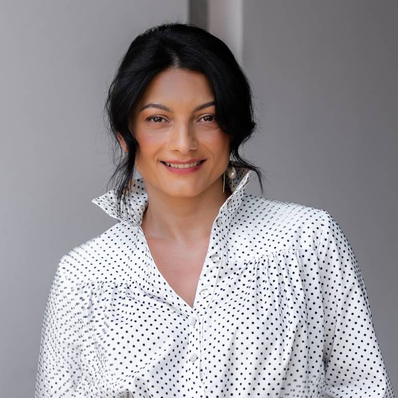 Photo of white woman with black hair wearing a white blouse