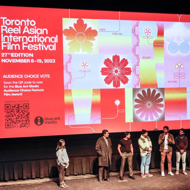 Image of 8 people standing on a stage with Toronto Reel Asian International banner in the background. 