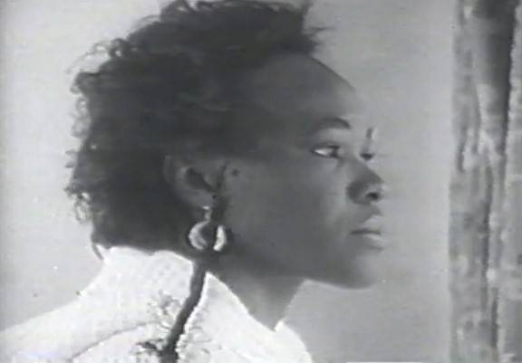 A black woman is pictured in black and white sitting in profile.