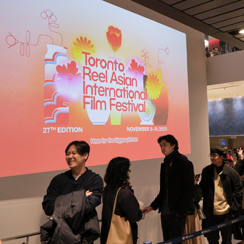 Image of a line up at Toronto Reel Asian Festival with festival graphics projected onto the wall.