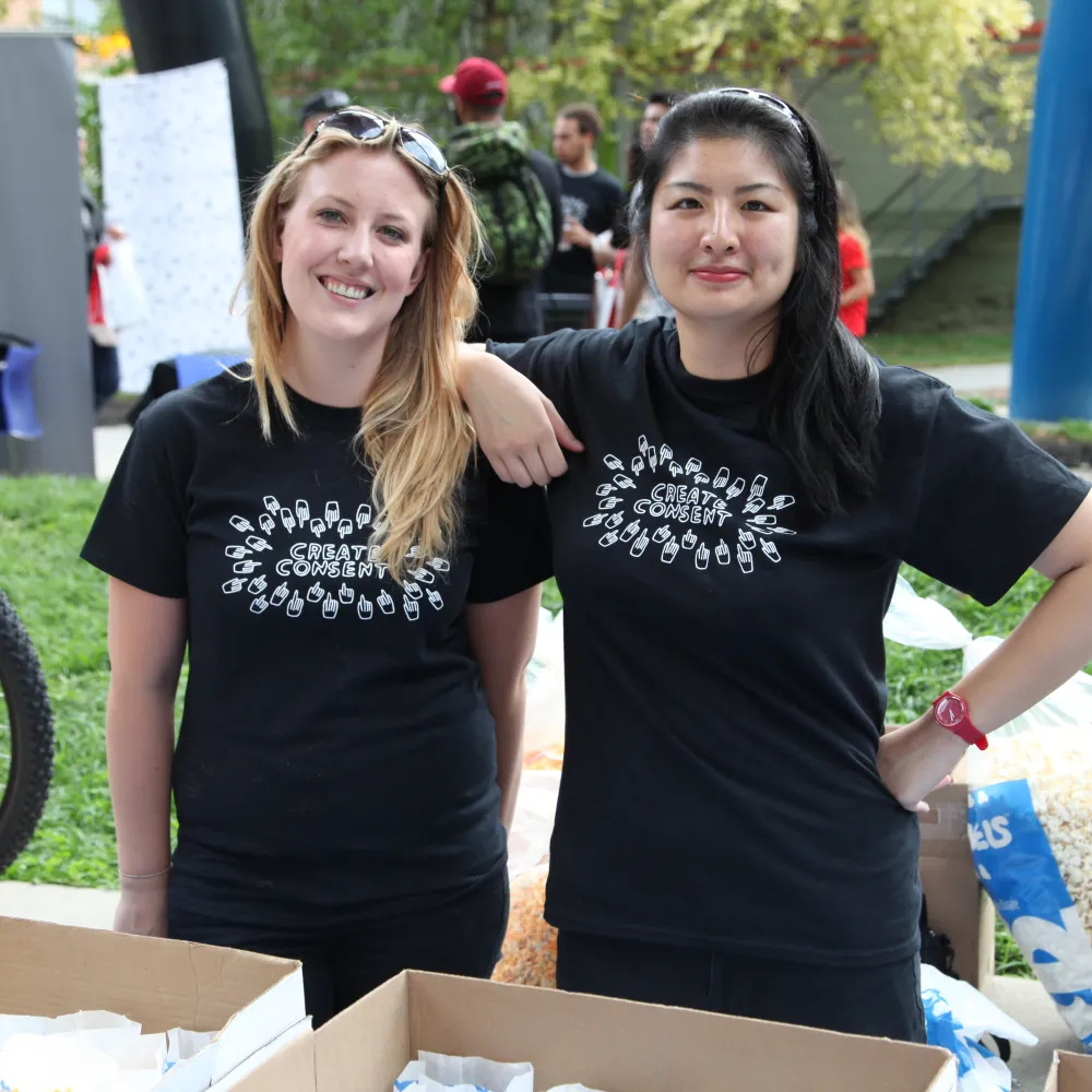 Two people smiling in black t-shirts.