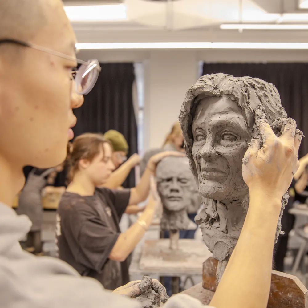 Person working on a clay bust.