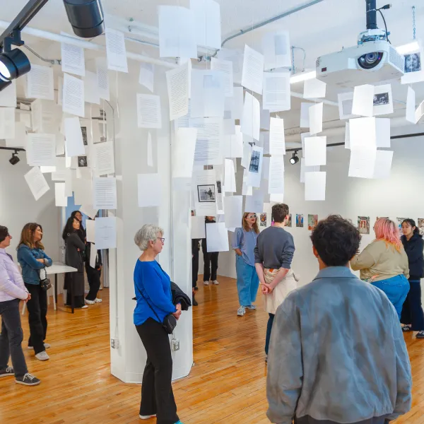 Gallery full of people with paper hanging from the ceiling